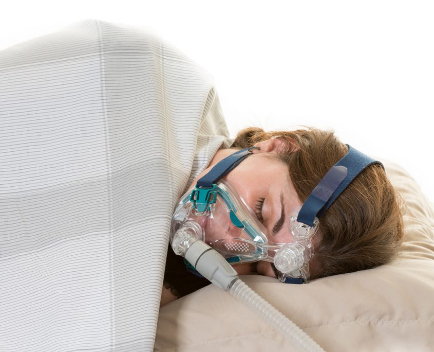 Hispanic woman sleeping and wearing the CPAP mask for the sleep apnea treatment