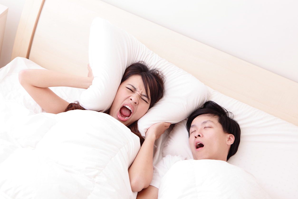 Young woman disturbed by the snores of her husband in the bedroom at home, asian family