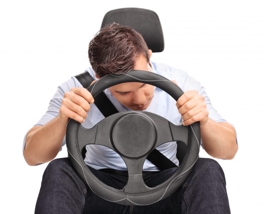 Studio shot of a young driver sleeping while driving isolated on white background