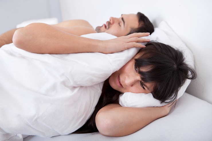 Young woman suffering from snoring boyfriend in bed